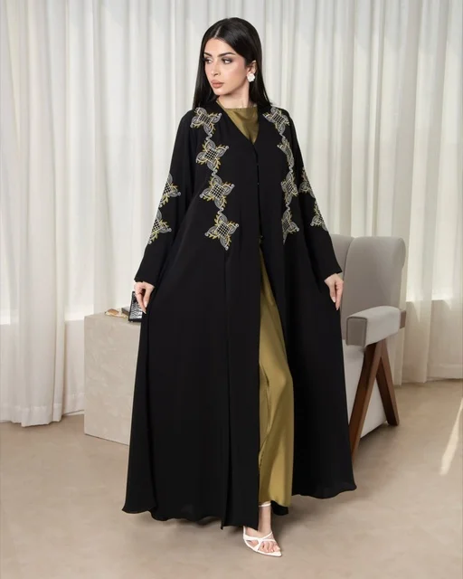 Wearing a modern women's outfit, an Arab Gulf Saudi woman wearing an embroidered black abaya, beauty, elegance, and attention to external appearance. Wearing a modern women's outfit, an Arab Gulf Saudi woman wearing an embroidered black abaya, beauty, elegance, and attention to external appearance.