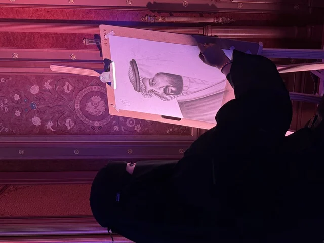 فنانة سعودية تقوم برسم لوحة فنية لولى العهد فى فعاليات ملتقى ريادة الأعمال وأنماط العمل الحديث (DeveGo 2025) في مركز الملك عبدالعزيز الدولي للمؤتمرات بمدينة الرياض، الفترة من 21 وحتى 23 من ديسمبر 2025 ، تجمع رواد الأعمال والخبراء والزوار ، مستقبل العمل الحر والتقنيات الحديثة