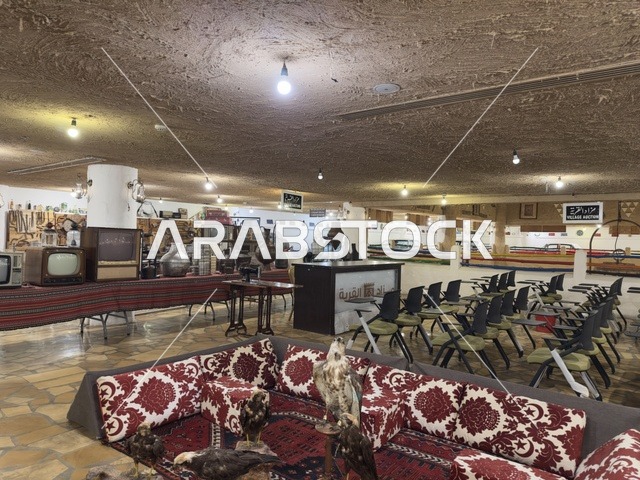 منطقة جلوس تقليدية منخفضة مغطاة بأقمشة منقوشة باللونين الأحمر والأبيض، الحفاظ على التراث المحلي وعرضه للزوار، القرية الشعبية التراثية متحف ومطعم بارز يقع على كورنيش الدمام في المملكة العربية السعودية،  بيئة ريفية أو تاريخية.