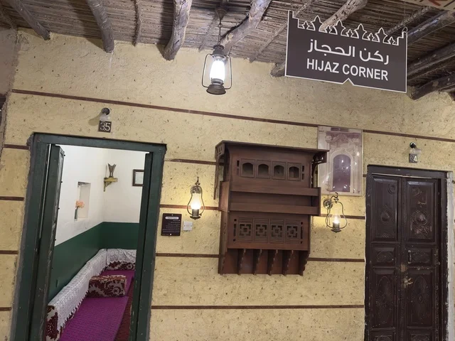 The sign of the Hijaz corner is hanging from a roof made of straw and wood, in a rural or historical environment, preserving local heritage and showcasing it to visitors. The popular heritage village is a prominent museum and restaurant located on the Corniche of Dammam in the Kingdom of Saudi Arabia.