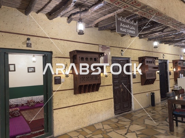 Preserving local heritage and showcasing it to visitors, a sign for the Hijaz corner hanging from a roof made of straw and wood, a rural or historical environment, the traditional folk village is a prominent museum and restaurant located on the Corniche of Dammam in the Kingdom of Saudi Arabia.