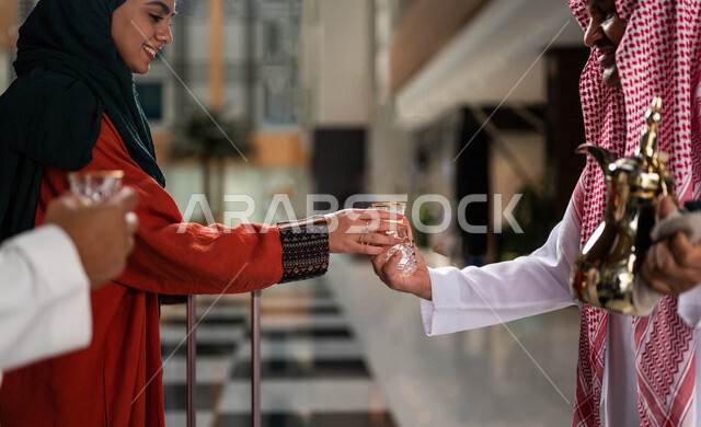 صورة مقربة لرجل سعودي يقوم بتقديم القهوة العربية الساخنة للسيّاح في بهو الفندق السياحي ، سياحة وفندقة ، زوجان سعوديان بإستضافتهم في الفندق ، قضاء أوقات ممتعة ، رحلة زوجية ممتعة ، تقديم حسن الضيافة للزوار الكرام داخل الفندق ، سياحة وسفر