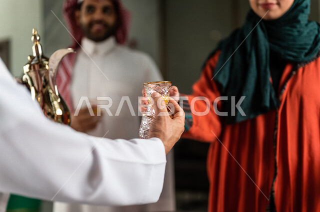 صورة مقربة لرجل سعودي يقوم بتقديم القهوة العربية الساخنة للسيّاح في بهو الفندق السياحي ، سياحة وفندقة ، زوجان سعوديان بإستضافتهم في الفندق ، قضاء أوقات ممتعة ، رحلة زوجية ممتعة ، تقديم حسن الضيافة للزوار الكرام داخل الفندق ، سياحة وسفر