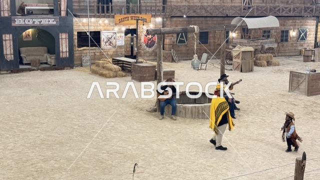 Southwest Town (Cowboy) in Al-Zahra neighborhood on Al-Aziz Road in Jeddah in 2025, buildings in classic Western style, various outdoor activities, a recreational tourist destination, a place for King Abdul to spend enjoyable time in the Kingdom of Saudi Arabia, wearing American cowboy attire.