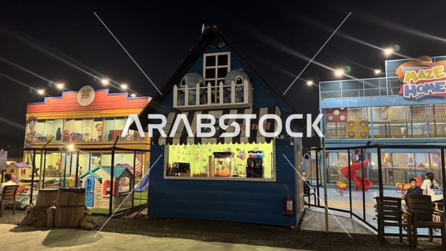 An entertainment game for children in the South West (Cowboy) town in the Al-Zahra neighborhood on King Abdulaziz Road in Jeddah for the year 2025, featuring buildings in classic Western style, a tourist entertainment destination, a place to have a good time in the Kingdom of Saudi Arabia, wearing American cowboy attire.