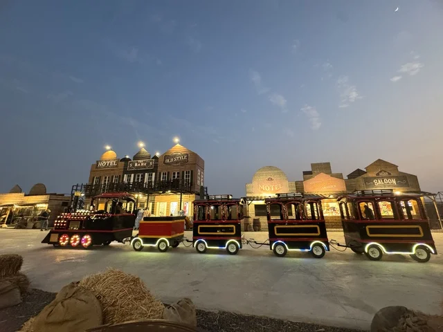 A train for transportation within the South West (Cowboy) town in the Al-Zahra neighborhood on King Abdulaziz Road in Jeddah in 2025, buildings in the classic Western style, a place to have a good time in the Kingdom of Saudi Arabia, wearing American cowboy attire.
