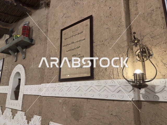 لوحة مؤطرة معلقة على الجدار تحتوي على نص مكتوب بخط عربي تقليدي، صممت القرية لتعكس العمارة التقليدية للمنطقة، القرية الشعبية التراثية متحف ومطعم بارز يقع على كورنيش الدمام في المملكة العربية السعودية