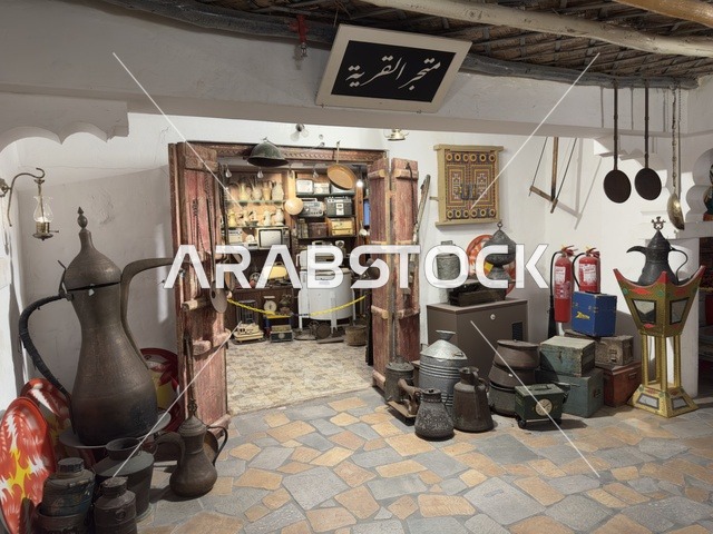 رفوف داخل المتجر مليئة بأدوات مطبخ تقليدية، متجر القرية يبيع أدوات منزلية وأواني قديمة وتراثية، صممت القرية لتعكس العمارة التقليدية للمنطقة، القرية الشعبية التراثية متحف ومطعم بارز يقع على كورنيش الدمام في المملكة العربية السعودية