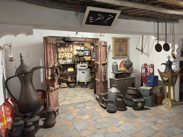 رفوف داخل المتجر مليئة بأدوات مطبخ تقليدية، متجر القرية يبيع أدوات منزلية وأواني قديمة وتراثية، صممت القرية لتعكس العمارة التقليدية للمنطقة، القرية الشعبية التراثية متحف ومطعم بارز يقع على كورنيش الدمام في المملكة العربية السعودية