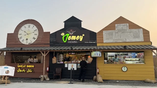 A store selling drinks and snacks in the South West (Cowboy) town in the Al-Zahra neighborhood on King Abdulaziz Road in Jeddah for the year 2025, wearing American cowboy attire, a recreational tourist destination, a place to have a good time in the Kingdom of Saudi Arabia, buildings in the classic Western style.