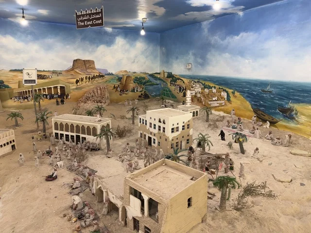 لوحة جدارية مرسومة تُظهر قوارب شراعية في البحر،لافته باللغة العربية والانكليزية الساحل الشرقي البحري، صممت القرية لتعكس العمارة التقليدية للمنطقة، القرية الشعبية التراثية متحف ومطعم بارز يقع على كورنيش الدمام في المملكة العربية السعودية