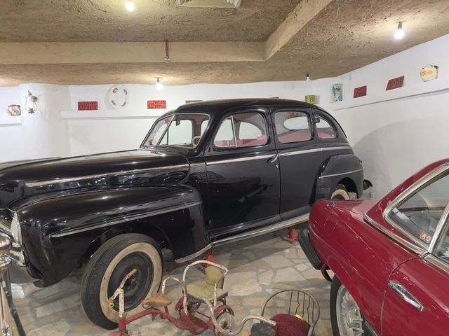 The car in the picture has a classic black paint job and white wall tires. The village is designed to reflect the traditional architecture of the area. The heritage folk village is a prominent museum and restaurant located on the Corniche of Dammam in the Kingdom of Saudi Arabia.