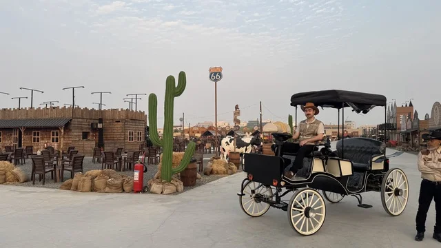 سيارة بشكل عربة حصان تقليدية للتنقل في بلدة ساوث ويست (الكاوبوي) في حي الزهراء على طريق الملك عبد العزيز في مدينة جدة لعام 2025، ارتداء زي الكاوبوي الامريكية، وجهه سياحية ترفيهية، مكان لقضاء وقت ممتع في المملكة العربية السعودية، مباني على الطراز الكلاسيكي الغربي