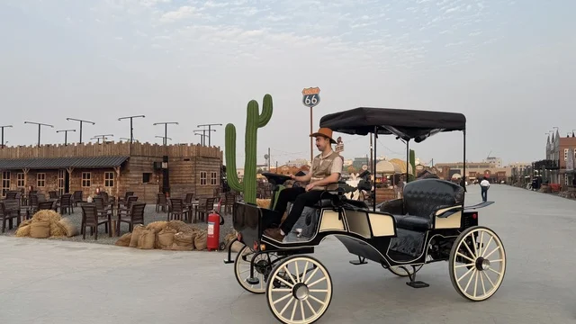 سيارة بشكل عربة حصان تقليدية للتنقل في بلدة ساوث ويست (الكاوبوي) في حي الزهراء على طريق الملك عبد العزيز في مدينة جدة لعام 2025، ارتداء زي الكاوبوي الامريكية، وجهه سياحية ترفيهية، مكان لقضاء وقت ممتع في المملكة العربية السعودية، مباني على الطراز الكلاسيكي الغربي