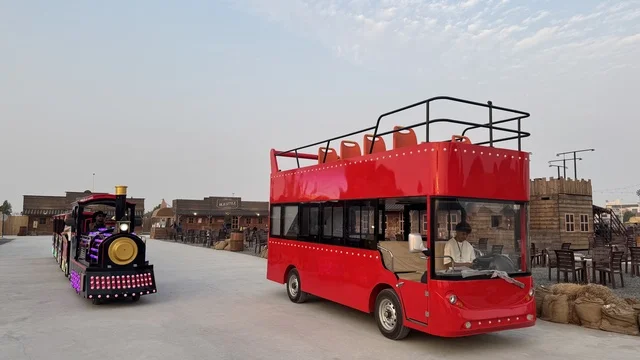 حافلة حمراء للتنقل في بلدة ساوث ويست (الكاوبوي) في حي الزهراء على طريق الملك عبد العزيز في مدينة جدة لعام 2025، ارتداء زي الكاوبوي الامريكية، وجهه سياحية ترفيهية، مكان لقضاء وقت ممتع في المملكة العربية السعودية، مباني على الطراز الكلاسيكي الغربي