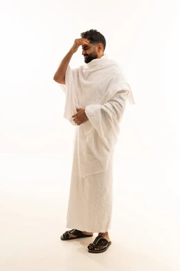 الإصابة بنوبات الشقيقة، إيماءات الصداع والإحساس بالمرض, آداء مناسك الحج والعمرة، الحاجه للعلاج وطلب المساعده, بورتريه لرجل مسلم خليجي سعودي مبتسم يرتدي ملابس الاحرام يمسك رأسه بيديه من شدة الألم, الشعور بالتعب والإرهاق, صورة الجسم بالطول الكامل، خلفية بيضاء