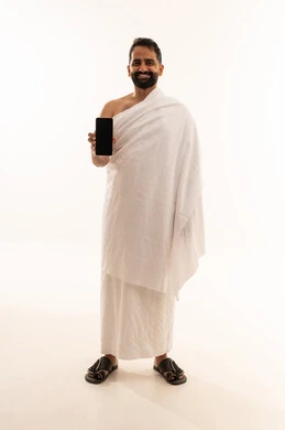 عرض شاشة سوداء عبر الهاتف المحمول، التوجه والانطلاق لزيارة بيت الله الحرام, بورتريه لرجل عربي خليجي سعودي يرتدي ملابس الاحرام يمسك بيدية الجوال ، أداء فريضة الحج و العمرة، استخدام التكنولوجيا الحديثة، صورة لكامل الجسم، خلفية بيضاء