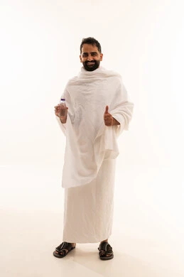 مفهوم القبول و الموافقة، الركن الخامس من أركان الاسلام لمن استطاع اليه سبيلا، الوقوف وشرب ماء زمزم بعد اداء الفريضه والنافله في مكه المكرمه، الاستعداد لاداء مناسك الحج والعمره والتقرب الى الله بالاعمال الصالحه، بورتريه لرجل عربي خليجي سعودي يرتدي ثوب الاحرام، الجسم بالطول الكامل، خلفية بيضاء