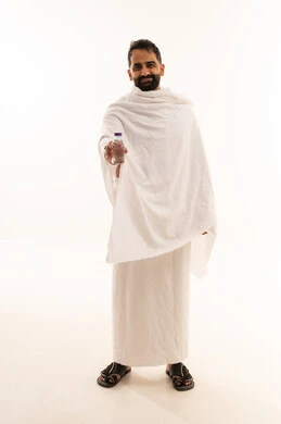 الوقوف وشرب ماء زمزم بعد اداء الفريضه والنافله في مكه المكرمه، الاستعداد لاداء مناسك الحج والعمره والتقرب الى الله بالاعمال الصالحه، بورتريه لرجل عربي خليجي سعودي يرتدي ثوب الاحرام، الركن الخامس من أركان الاسلام لمن استطاع اليه سبيلا، الجسم بالطول الكامل، خلفية بيضاء