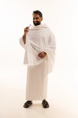الارتواء بماء زمزم، أداء مناسك الحج والعمرة، الاكثار من السوائل للحفاظ على الجسم من الجفاف، بورتريه لرجل عربي سعودي خليجي يرتدي زي الاحرام يقوم بشرب المياه العذب، الجسم بالطول الكامل، خلفية بيضاء