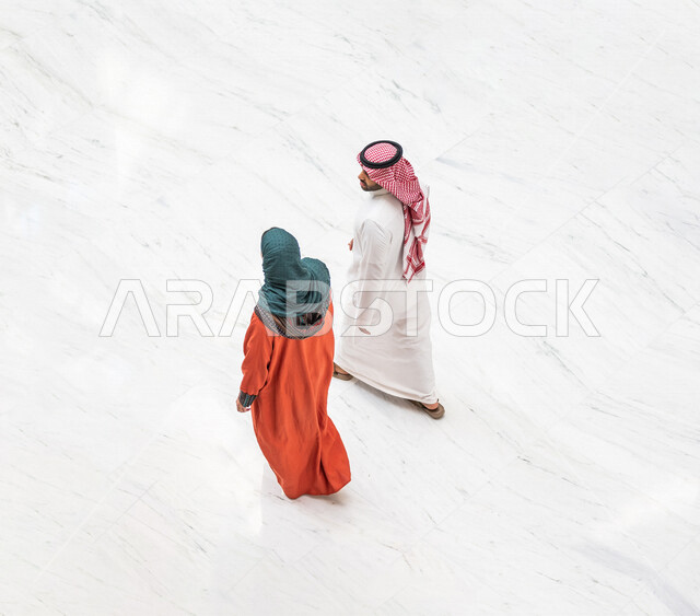 زاوية من أعلى لزوجان عربيان سعوديان سائحان يمشيان ويتجولان في بهو الفندق السياحي ، سياحة وفندقة ، قضاء أجمل الأوقات في أفضل الفنادق الخليجية ، رحلة زوجية ممتعة ، سياحة وسفر، أجواء عائلية ترفيهية ، عطلة نهاية الأسبوع ، مفهوم الأسرة السعيدة