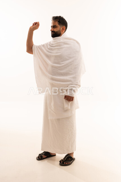 رمي جمرة العقبة في يوم النحر، أداء مناسك الحج والعمرة، بورتريه لرجل مسلم عربي سعودي خليجي يرتدي ملابس الاحرام يحمل بيده حصوى للقيام برجم ابليس، العبادة والتقرب الى الله، الجسم بالطول الكامل، خلفية بيضاء