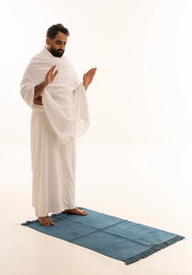 الخشوع والتوسل والتضرع لله، مفهوم العبادة والحفاظ على الصلوات، بورتريه لرجل عربي خليجي يرتدي ملابس الإحرام يرفع يديه لتكبيرة الإحرام يؤدي فريضة الصلاة، الركن الثاني من أركان الإسلام، صورة الجسم بالطول الكامل، خلفية بيضاء