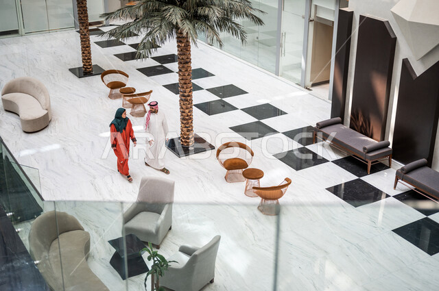 زاوية من أعلى لزوجان عربيان سعوديان سائحان يمشيان ويتجولان في بهو الفندق السياحي ، سياحة وفندقة ، قضاء أجمل الأوقات في أفضل الفنادق الخليجية ، رحلة زوجية ممتعة ، سياحة وسفر، أجواء عائلية ترفيهية ، عطلة نهاية الأسبوع ، مفهوم الأسرة السعيدة