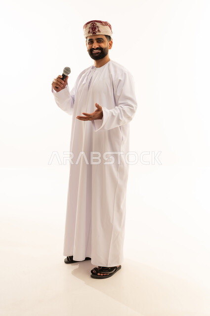 إلقاء المحاضرات وإقامة الندوات، تبادل الحوار والاستفادة من الخبرات، بورتريه لرجل عربي خليجي عماني يرتدي الدشداشة و العمامة ينظر الى الكاميرا بتعابير السرور، العمل في تقديم الفقرات والبرامج الفنية الترفيهية، الجسم بالطول الكامل، خلفية بيضاء
