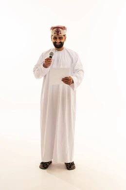 التدقيق في قراءة الملاحظات، ممارسة موهبه الغناء، اعداد التقارير الخاصة بالعمل، متابعة ومراجعة الخطط والمشاريع المكتبية، بورتريه لرجل عربي خليجي عماني يرتدي الدشداشة و العمامة ينظر الى الاوراق البيضاء يمسك بيده المايك، الجسم بالطول الكامل، خلفية بيضاء