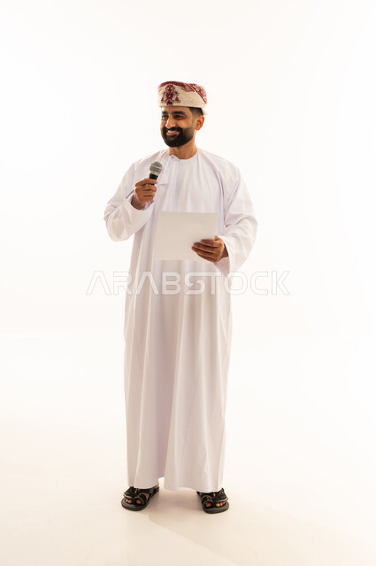 ممارسة موهبه الغناء، اعداد التقارير الخاصة بالعمل، متابعة ومراجعة الخطط والمشاريع المكتبية، بورتريه لرجل عربي خليجي عماني يرتدي الدشداشة و العمامة ينظر الى الاوراق البيضاء يمسك بيده المايك, التدقيق في قراءة الملاحظات، الجسم بالطول الكامل، خلفية بيضاء