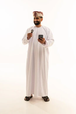 مواهب فنية في عالم الموسيقى، ممارسة هواية الغناء للتسلية والترفيه، الفن المسرحي الغنائي، تقديم العرض المسرحي، ببورتريه لرجل عربي خليجي عماني يرتدي الدشداشة و العمامة يحمل بيده الميكروفون و الهاتف المحمول ، الجسم بالطول الكامل، خلفية بيضاء