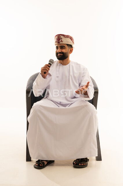 ايماءات وتعابير وجه و يدين تعبر عن الغناء والطرب، فن إلقاء الخطابات والندوات، التدريب الصوتي وتقديم البرامج الاذاعيه، بورتريه لرجل عربي خليجي عماني يرتدي الدشداشة و العمامة يجلس على الكرسى يمسك بيدية الميكروفون، خلفية بيضاء