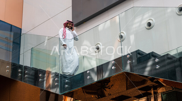 رجل خليجي سعودي ، يقوم بإجراء مكالمة هاتفية عبر الهاتف المحمول في داخل الفندق السياحي ، إستخدام أجهزة تقنية حديثة ، جلسة عمل، مفهوم إدارة الأعمال، عقد صفقات تجارية ، العمل عن بعد ، التسويق الإلكتروني، رحلة عمل ، سياحة وفندقة ، سياحة وسفر