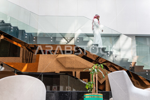 رجل خليجي سعودي ، يقوم بإجراء مكالمة هاتفية عبر الهاتف المحمول في داخل الفندق السياحي ، إستخدام أجهزة تقنية حديثة ، جلسة عمل، مفهوم إدارة الأعمال، عقد صفقات تجارية ، العمل عن بعد ، التسويق الإلكتروني، رحلة عمل ، سياحة وفندقة ، سياحة وسفر