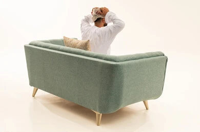 الانزعاج عند سماع خبر سيء، التفاجؤ من شيء ما، الشعور بالدهشة والاستغراب , بورتريه من الخلف لرجل عربي خليجي عماني يرتدي الدشداشة و العمامة يجلس على الاريكة يرفع يديه على رأسه بتعابير الصدمة, خلفية بيضاء