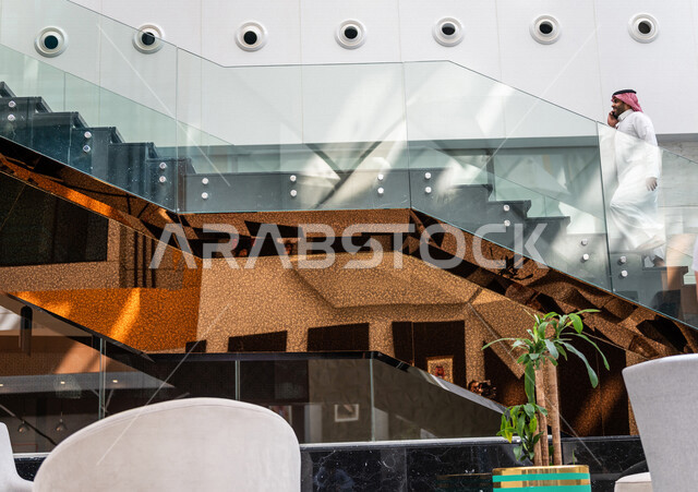 رجل خليجي سعودي ، يقوم بإجراء مكالمة هاتفية عبر الهاتف المحمول في داخل الفندق السياحي ، إستخدام أجهزة تقنية حديثة ، جلسة عمل، مفهوم إدارة الأعمال، عقد صفقات تجارية ، العمل عن بعد ، التسويق الإلكتروني، رحلة عمل ، سياحة وفندقة ، سياحة وسفر