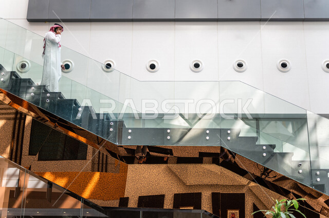 A Saudi Gulf man, making a phone call via a mobile phone inside the tourist hotel, using modern technical equipment, a working session, the concept of business management, making business deals, working remotely, e-marketing, a business trip, tourism and