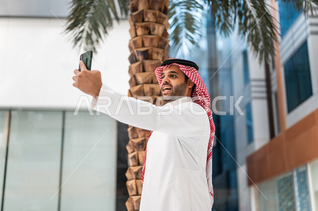 A Saudi Gulf man inside the hotel, making a video call via a mobile phone, tourism and hotel, entertainment and entertainment, using modern technology devices, spending fun times, using social media, selfies commemorative, live broadcast, advertisements
