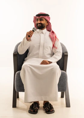 القاء الخطابات والكلمات باستخدام مكبر الصوت، القيام بالحوارات والنقاشات، بورتريه لرجل عربي خليجي عماني سعودي يرتدي الثوب الابيض و الشماغ يجلس على كرسي يحمل بيده مكبر الصوت، خلفية بيضاء