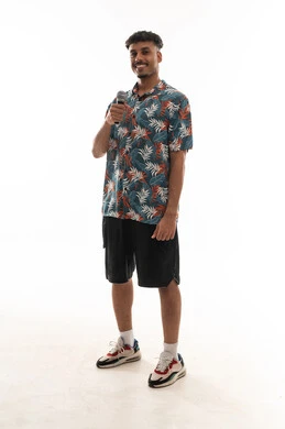 Looking at the camera while holding the microphone, an Arab Gulf Omani man wearing casual attire is singing into a loudspeaker, gestures of happiness, having a good time, full-body shot, portrait with a white background.