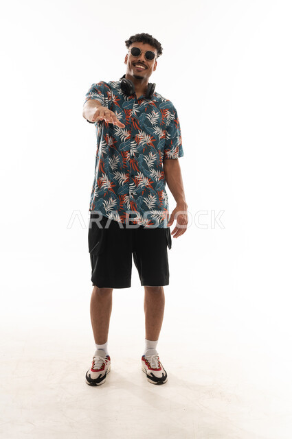 A Gulf Arab Omani man wearing casual attire feels happy, raising his arm and spreading his fingers in a smile, portrait with a white background, full body.