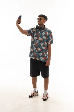 Taking selfies with a mobile phone camera, an Arab Gulf Omani man wearing casual attire, gestures of happiness and smiling, portrait with a white background, full body.