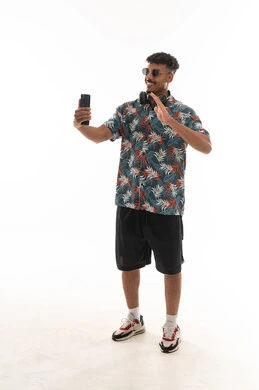 التلويح بكف اليد اشارة الترحيب و السلام , رجل عربي خليجي عماني يرتدي الزي الكاجوال يقوم باجراء مكالمة فيديو مباشرة , بورتريه خلفية بيضاء , الجسم بالطول الكامل