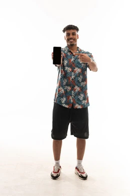 الاشارة باصبع السبابة للهاتف المحمول , رجل عربي خليجي عماني يرتدي زي كاجوال يعرض شاشة سوداء فارغة امام الكاميرا , بورتريه خلفية بيضاء , الجسم بالطول الكامل