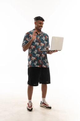 محادثات فيديو جماعية مباشرة باستخدام التطبيقات المتعددة في الاجهزة التقنية الحديثة , رجل عربي خليجي عماني يرتدي الزي الكاجوال يحمل جهاز الحاسب المتنقل , التلويح بكف اليد علامة الترحيب و السلام , ايماءات السعادة و الفرحة , بورتريه خلفية بيضاء , الجسم بالطول الكامل