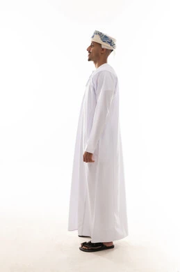 رجل عربي خليجي عماني يرتدي الدشداشة البيضاء و العمامة يقف بالجانب امام الكاميرا , ايماءات السعادة , لقطة جانبية , الجسم بالطول الكامل , بورتريه خلفية بيضاء