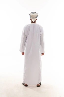 رجل عربي خليجي عماني يرتدي الدشداشة البيضاء و العمامة يققف بالخلف امام الكاميرا , الجسم بالطول الكامل , بورتريه خلفية بيضاء