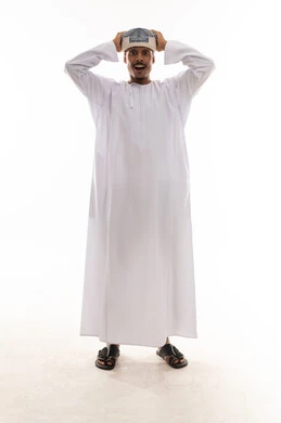 تعابير الذهول و الاندهاش , رجل عربي خليجي عماني يرتدي الدشداشة البيضاء و العمامة يضع يده فوق راسه اشارة الي الشعور بالدهشة , النظر للكاميرا , بورتريه خلفية بيضاء , الجسم بالطول الكامل
