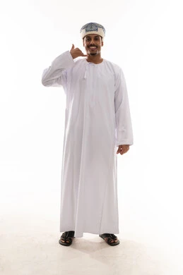 Raising the pinky and thumb is a signal to request a callback. An Arab Gulf Omani man wearing a white dishdasha and turban stands in front of the camera, with gestures of happiness and a smile, full-body shot, white background portrait.